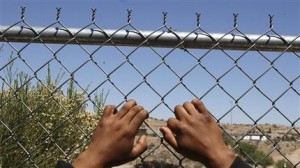 Un hombre pone sus manos en una cerca de alambre con vista hacia Estados Unidos desde una estación aduanera mexicana tras de que lo detuviera la Patrulla Fronteriza estadounidense en Arizona y lo regresara a México, en la localidad mexicana de Nogales, el 18 de mayo de 2006. (AP Foto/Gregory Bull)