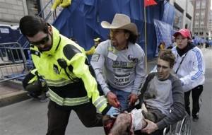 Una persona herida es retirada en una silla de ruedas del lugar donde hubo dos explosiones cerca de la línea de meta del Maratón de Boston, el lunes 15 de abril de 2013. (AP Foto/Charles Krupa)
