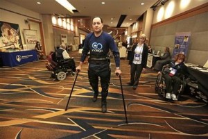 En esta foto del 6 de mayo del 2013, Michael Gore, paralizado de la ciuntura para abajo en un accidente de trabajo, camina gracias al robot portátil Indego bajo la supervisión de la terapeuta física Clare Hartigan durante una reunión de la Asociación Estadounidense de Lesiones Espinales en un hotel céntrico de Chicago (AP Foto/M. Spencer Green)