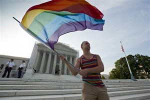 El defensor de los derechos de los homosexuales Vin Testa ondea una bandera de varios colores frente a la Corte Suprema en Washington, el miércoles 26 de junio de 2013. La corte determinó el miércoles que las parejas del mismo sexo casadas legalmente deberían tener los mismos beneficios federales con que cuentan las parejas heterosexuales. (Foto AP/J. Scott Applewhite)