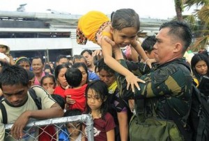 Persona militar fillipino trata de dar prioridad a los niños y las mujeres entre miles de personas que esperaban ser evacuadas por avión en Tacloban, Filipinas, el martes 12 de noviembre de 2013. (Foto AP/Wally Santana)