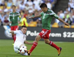 Michael McGlinchey, izquierda, de la selección de fútbol de Nueva Zelanda, disputa el balón con el mexicano Oribe Peralta en el partido de vuelta de su serie de repechaje para el Mundial, en el Estadio Westpac de Wellington, Nueva Zelanda, el miércoles 20 de noviembre de 2013. México ganó el partido 4-2 para clasificar al Mundial. México había ganado 5-1 en el duelo de ida en el estadio Azteca. (Foto AP/SNPA, Ross Setford)