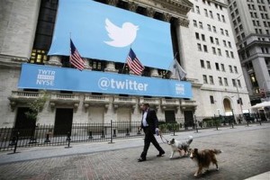 Un hombre camina junto a sus perros frente a la sede de la Bolsa de Valores de Nueva York, que está decorada con el cartel de Twitter, el 7 de noviembre del 2013. Twitter debutó en la bolsa el jueves ante una intensa demanda y un alza en el precio de sus acciones. (Foto AP/Mark Lennihan)