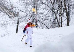 Foto concedida por el Comité de la Organización de los Juegos Olímpicos de Invierno 2014 de Sochi muestra como un hombre porta la antorcha olímpica mientras camina en la nieve el 5 de enero de 2014 en Kirov, Moscú (SOCHI 2014 ORGANIZING COMMITTEE/AFP)