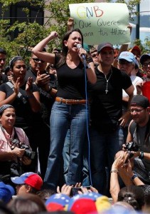 La congresista de oposición María Corina Machado habla ante manifestantes en Caracas, Venezuela, el sábado 15 de febrero de 2014. Las siglas en el letrero significan "Guardia Nacional Bolivariana". (Foto AP/Fernando Llano)