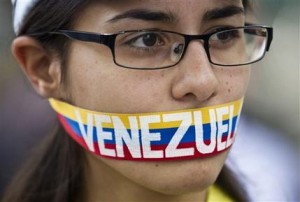 Una manifestante antigubernamental se cubre la boca con una cinta con los colores de la bandera venezolana en una protesta frente a una oficina de la OEA en Caracas, Venezuela, el viernes 21 de marzo de 2014. (AP Photo/Esteban Felix)