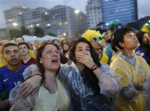 Hinchas de Brasil lloran al ver la derrota de su selección ante Alemania en la semifinal de la Copa del Mundo, mediante una pantalla gigante emplazada en la playa de Copacabana, el martes 8 de julio de 2014 (AP Foto/Leo Correa)