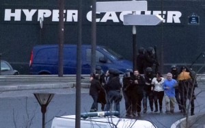 Agentes de seguridad escoltan a los rehenes liberados en el mercado "Hyper Cacher", en el distrito judío de París. (AP Photo/Michel Euler)