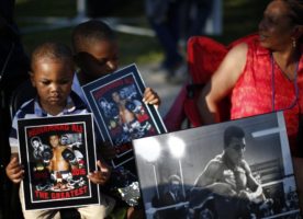 Brandon Liggons, 2, (L) holds an image of Muhammad Ali during the funeral procession for the three-time heavyweight boxing champion in Louisville, Kentucky, U.S., June 10, 2016.  REUTERS/Lucy Nicholson