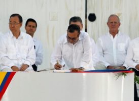 El líder rebelde marxistas Rodrigo Londono (C), mejor conocido como Timochenko, firma el  acuerdo que pone fin a un conflicto armado con medio siglo de duración y que mantuvo a Colombia herida, ante la mirada de los 2.500 invitados que asistieron a la ceremonia, vestidos de blanco, donde hubo 15 mandatarios, como el cubano Raúl Castro. También estuvieron el secretario de Estado de Estados Unidos, John Kerry, y víctimas del conflicto.  REUTERS/John Vizcaino